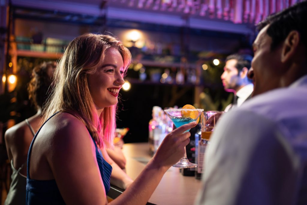 Beautiful young couple having fun, drinking alcohol cocktail in